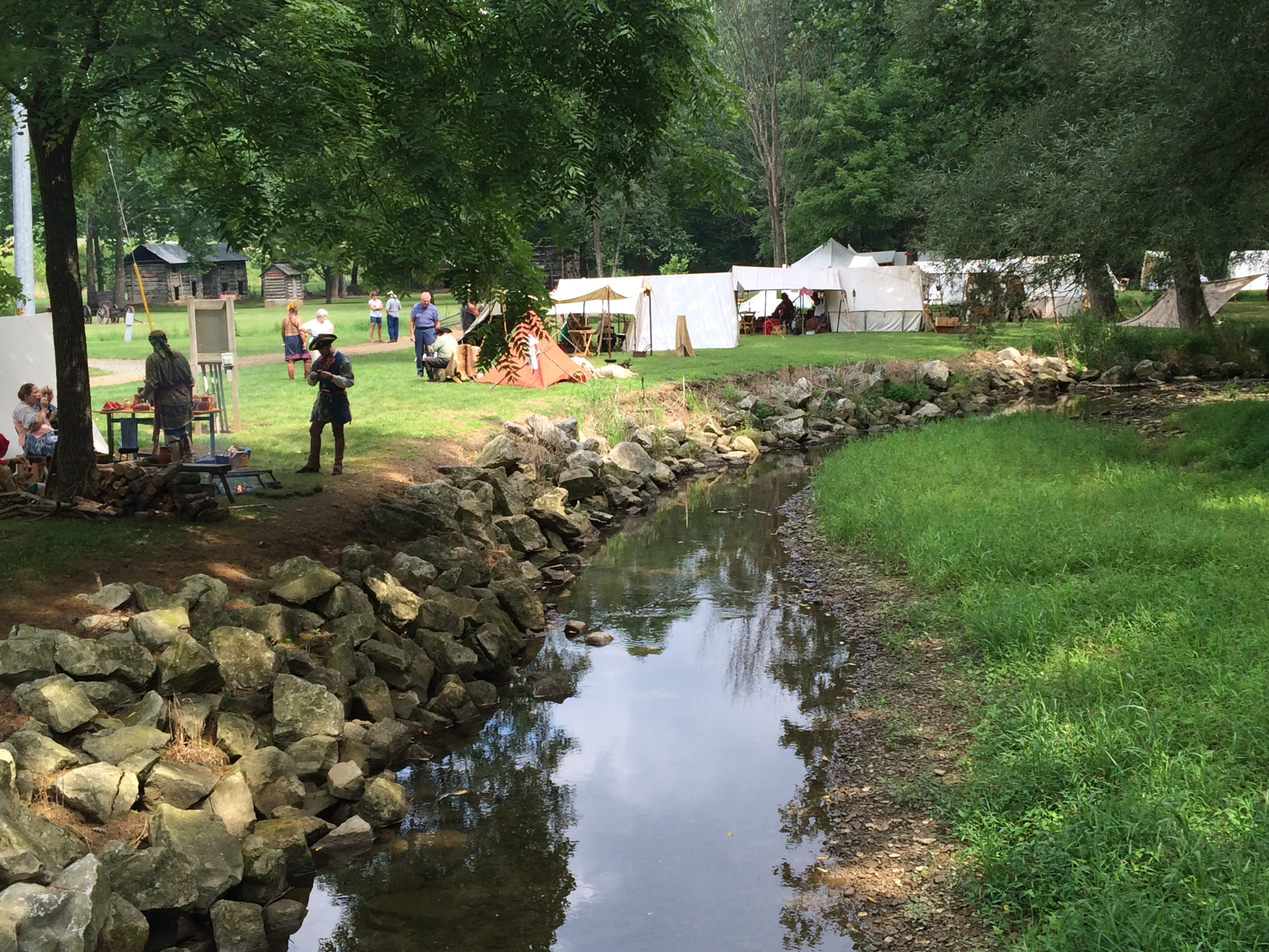 Tents, participants and visitors by the creek at the Grist Mill.
