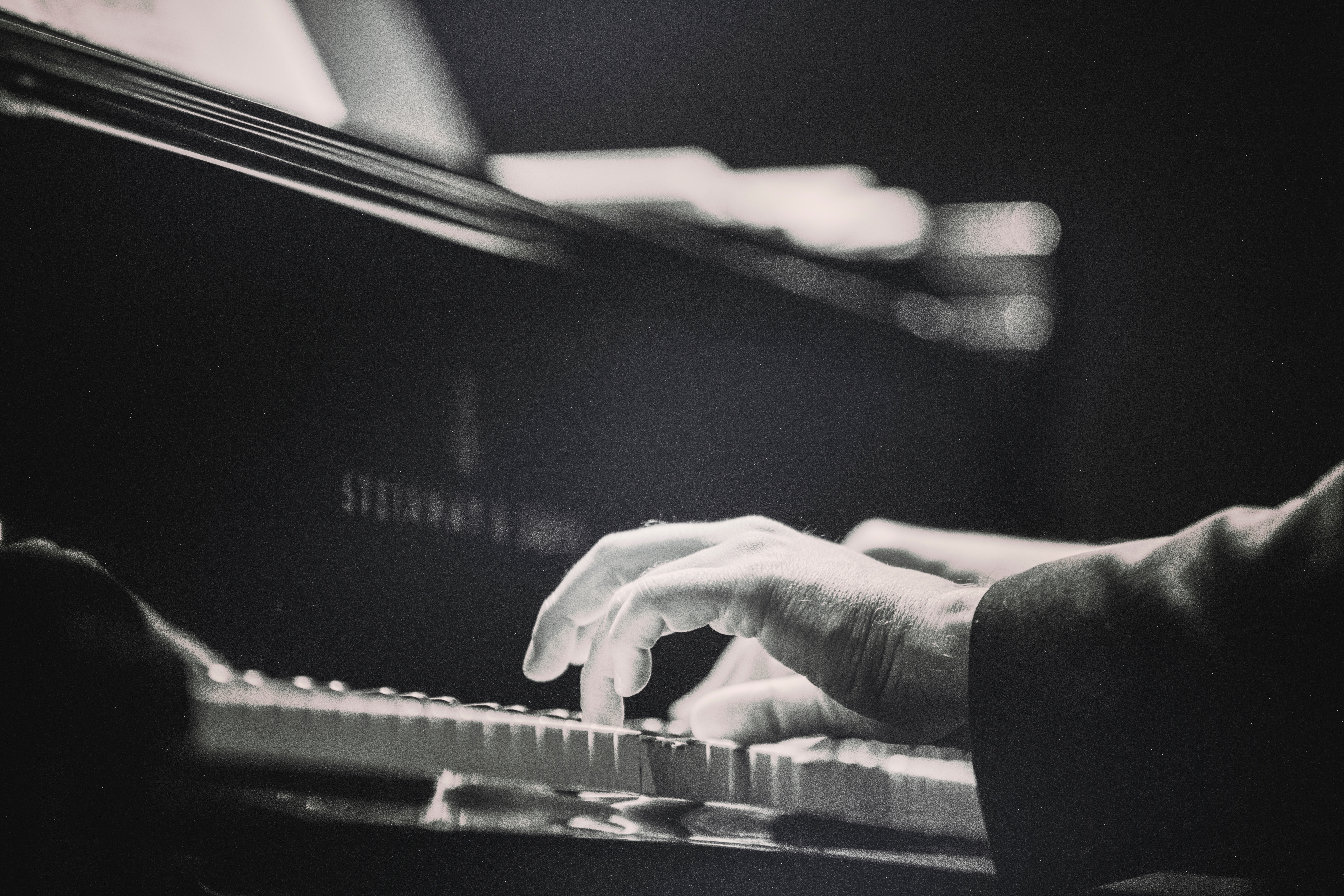 Black and white picture of hands on piano keys.