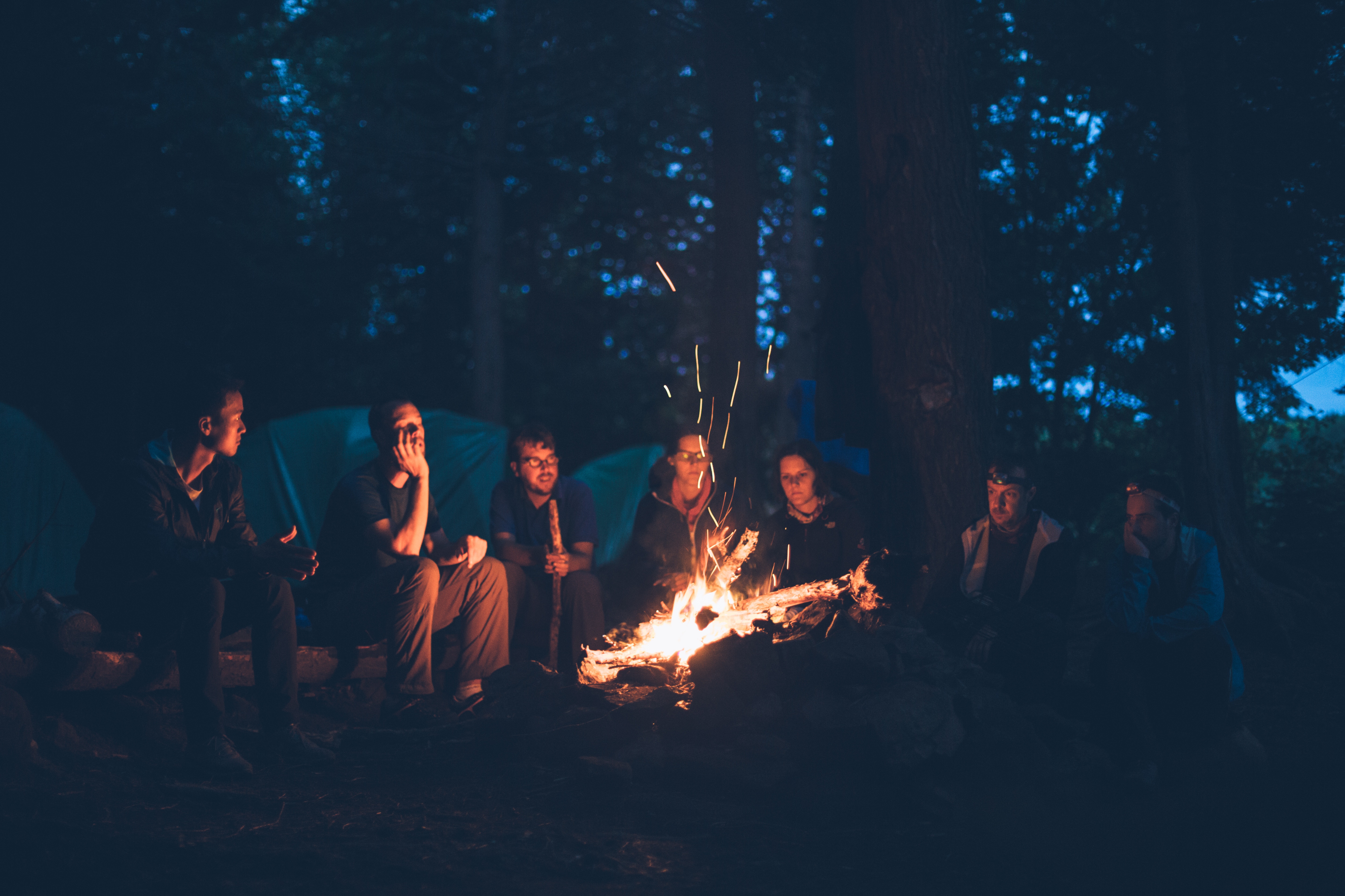 People sitting around evening campfire.