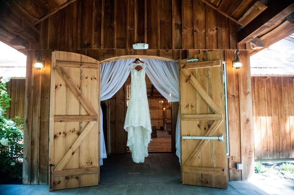 White wedding dress hanging up in barn doorway.