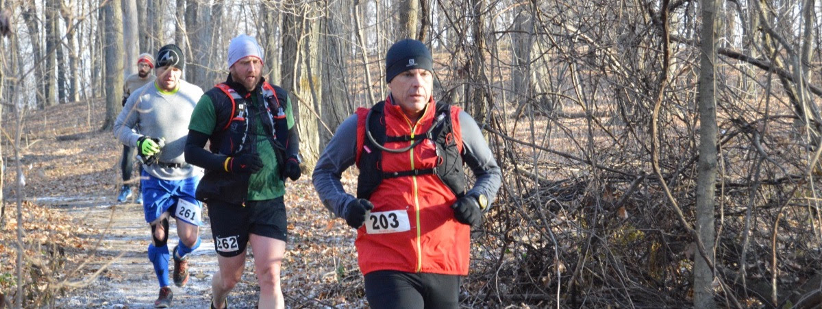 Man running trail race in woods.